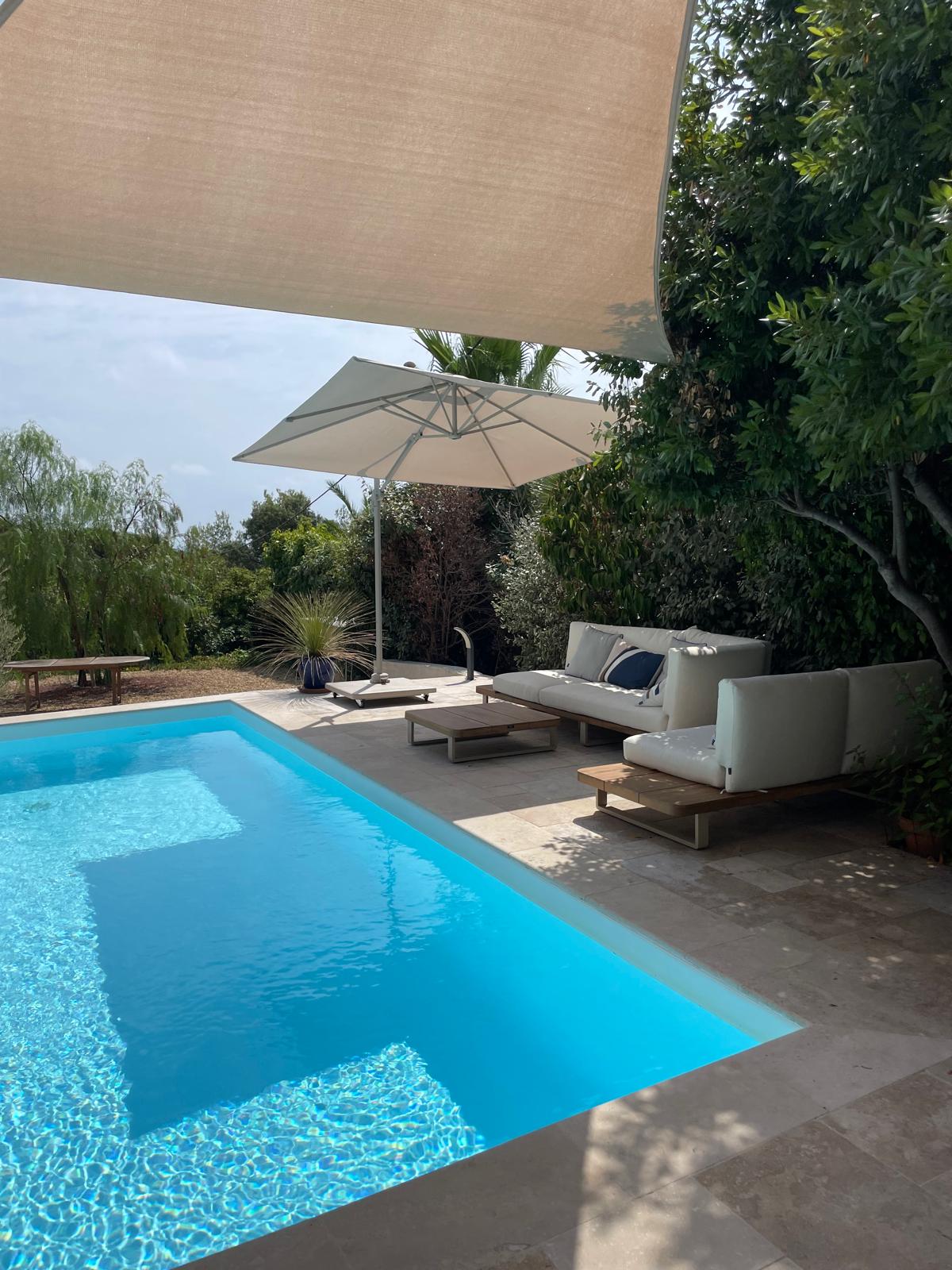 Poolside lounge seating under a large shade sail and parasol