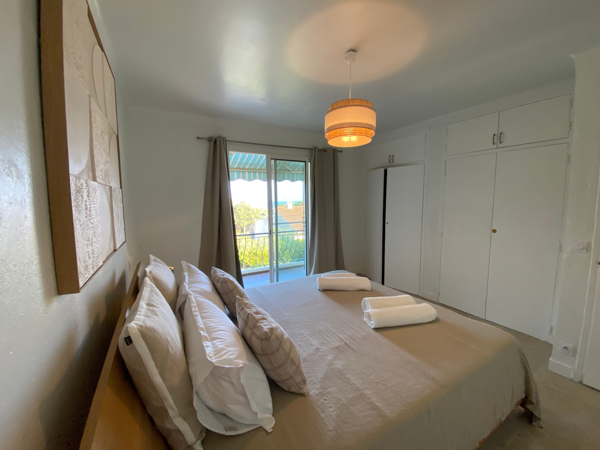 Beige bedroom with a double bed and doors opening onto a private balcony