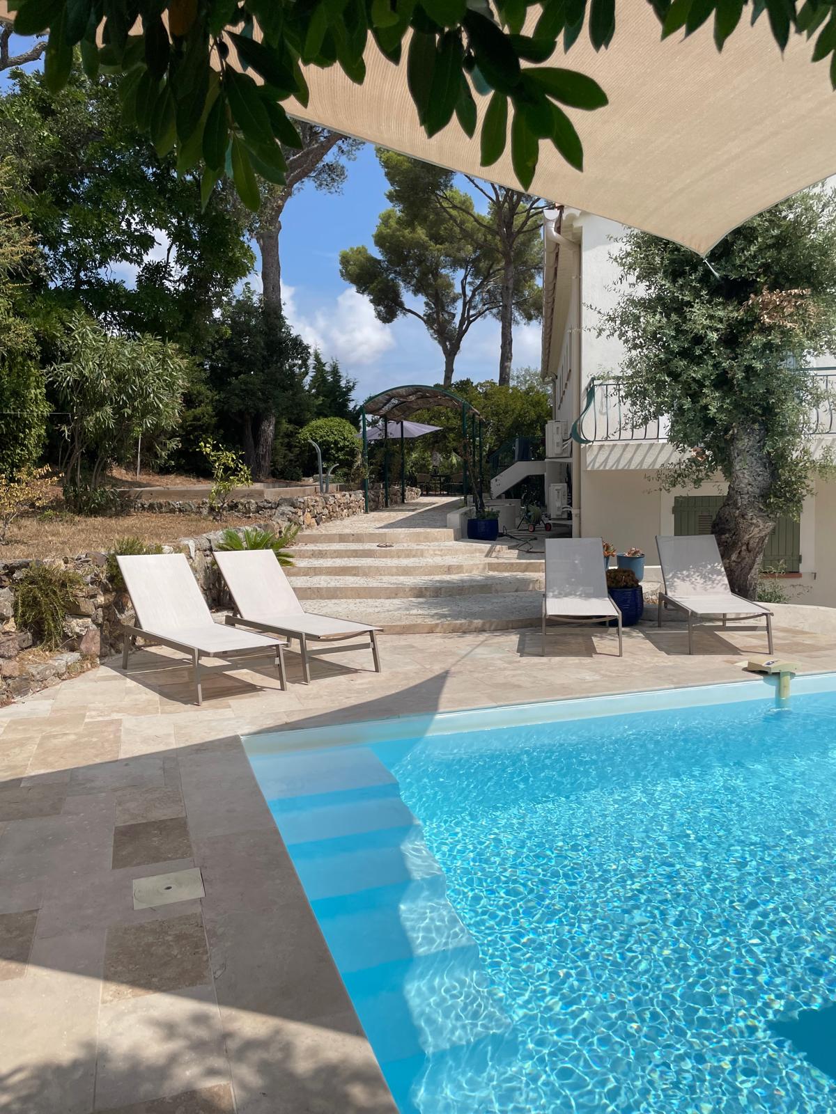 Sun loungers beside the pool with stone steps leading up to the villa garden