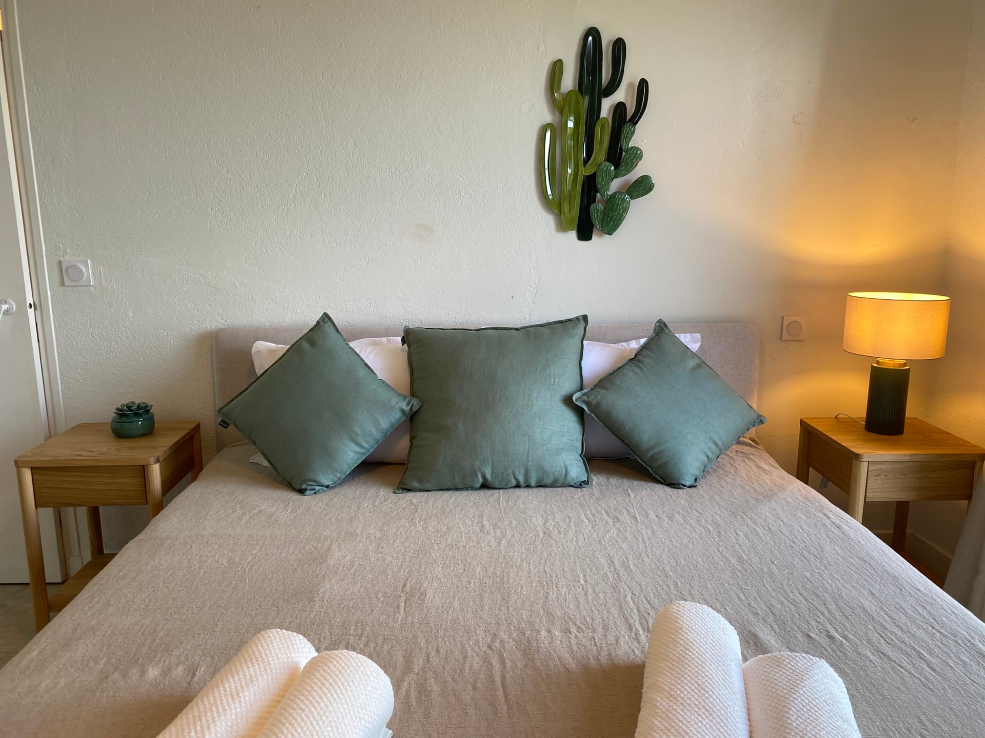 Bedroom with green cushions and framed cactus prints above the bed