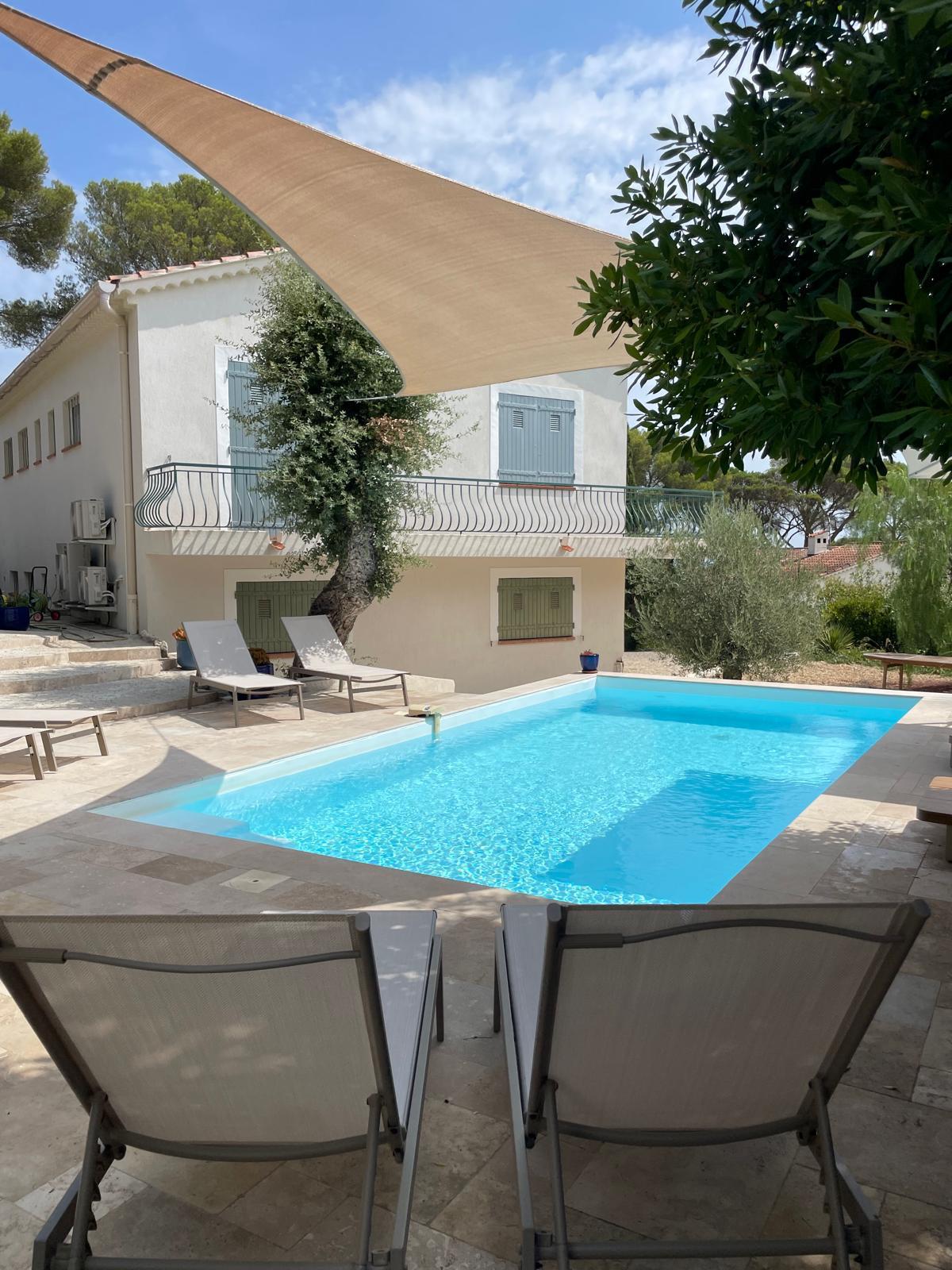 The pool under its shade sail with the villa and olive tree behind
