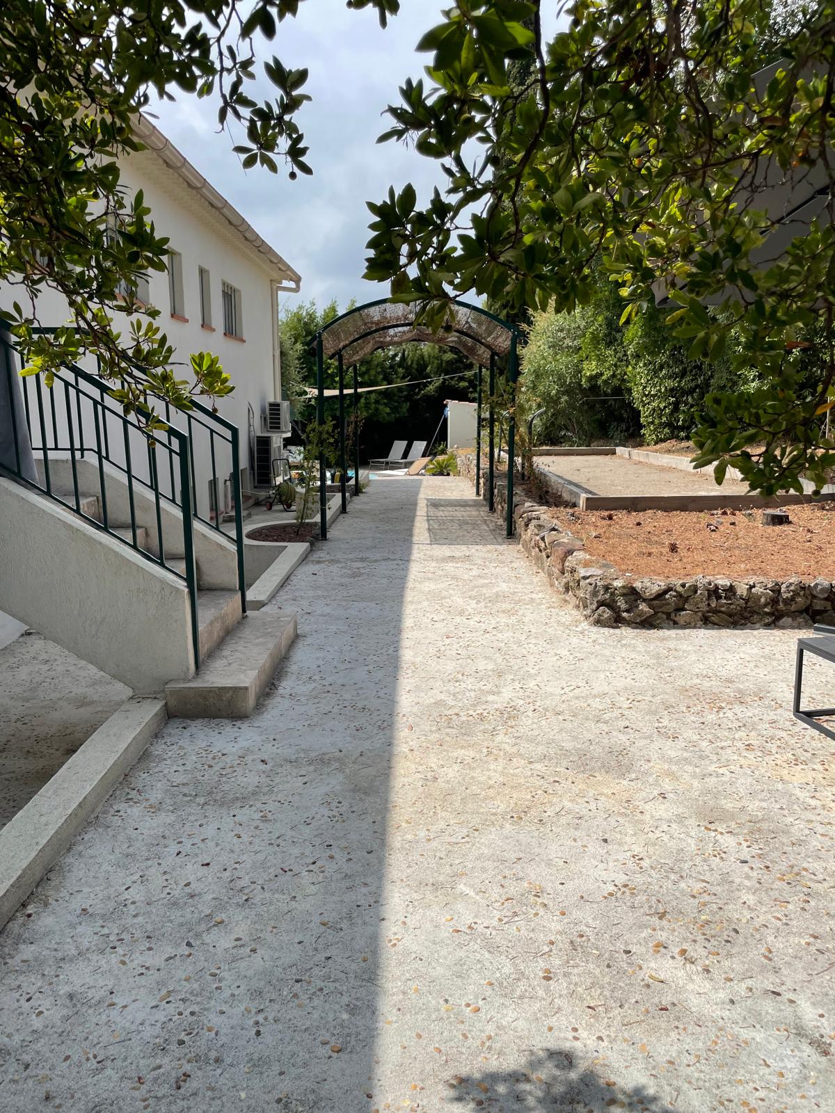 Path along the villa leading past the petanque court and pergola to the pool