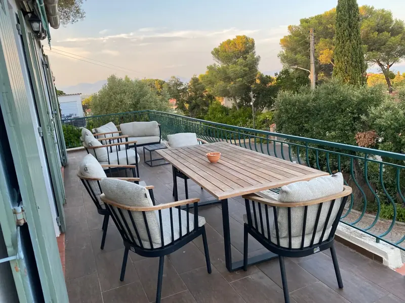 Covered terrace with wooden dining furniture and cushioned seating
